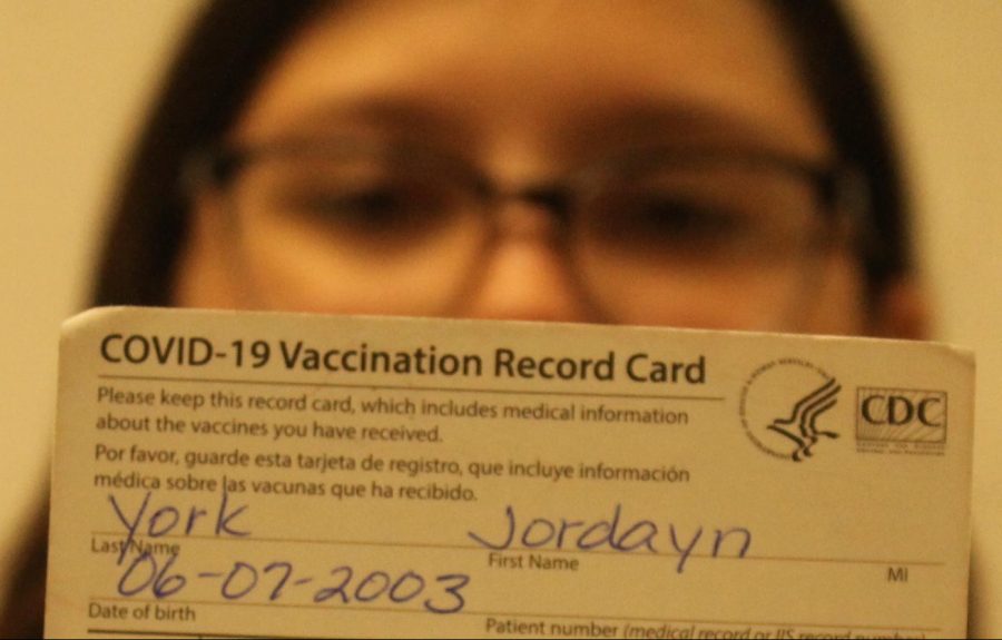 Senior Jordayn York holds up her vaccination card.