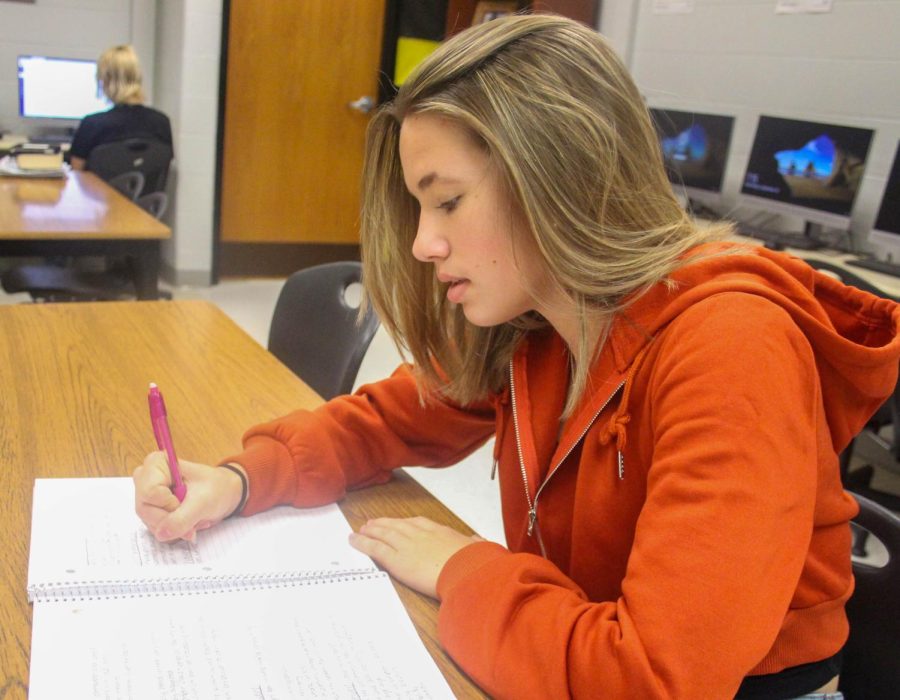 Junior Bailey Scarborough takes down her note on paper in her classroom.