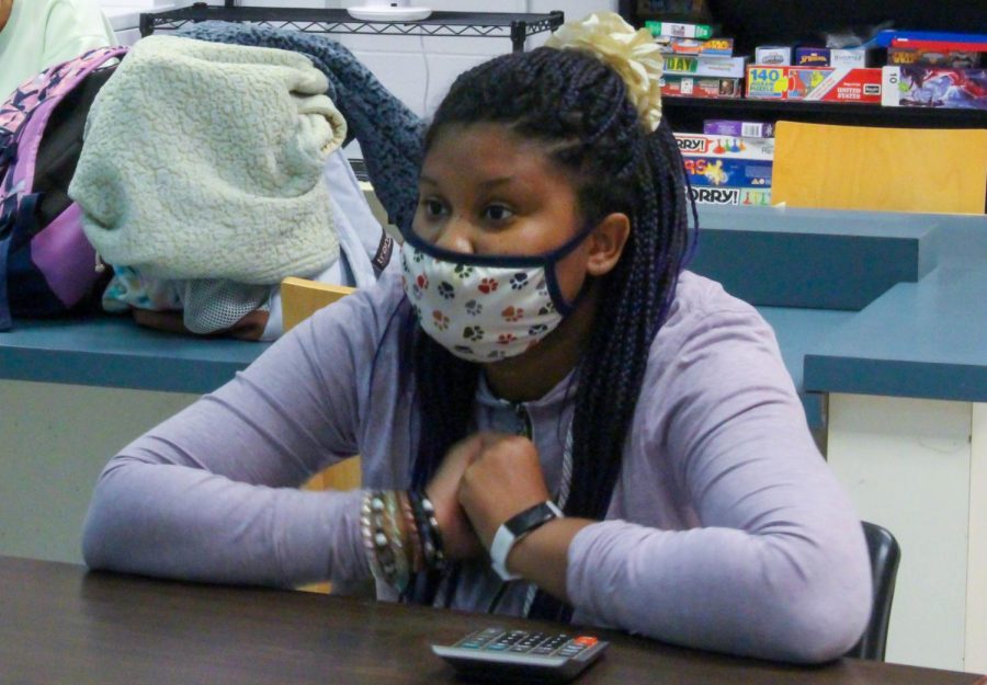 A student sits in the special education class, learning about money. They learn about how to save, spend and use money in their lives and how their money affects them.