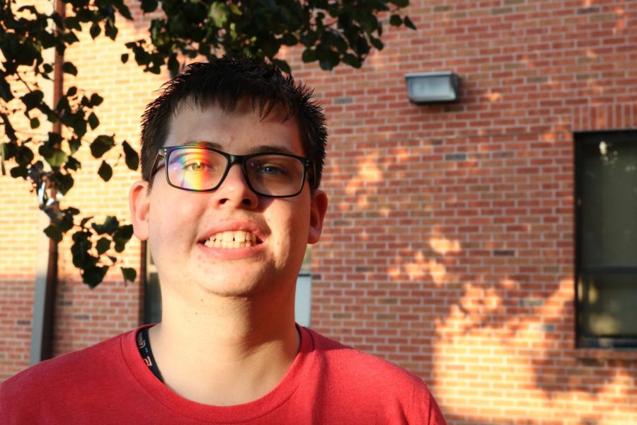 Senior Dallas Curativo poses with a rainbow being reflected on his face.