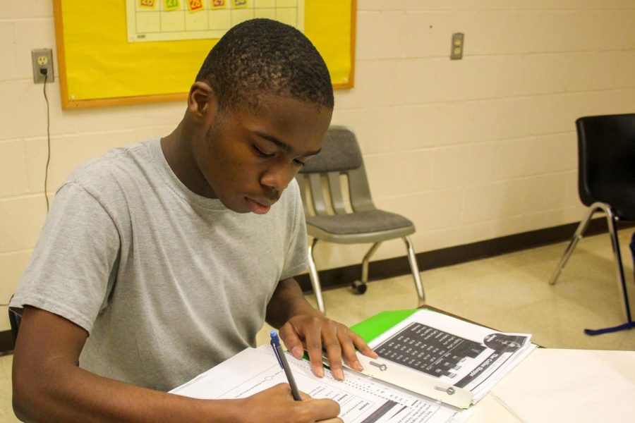 Senior Malik Wallace sits at his desk and does work in the classroom.