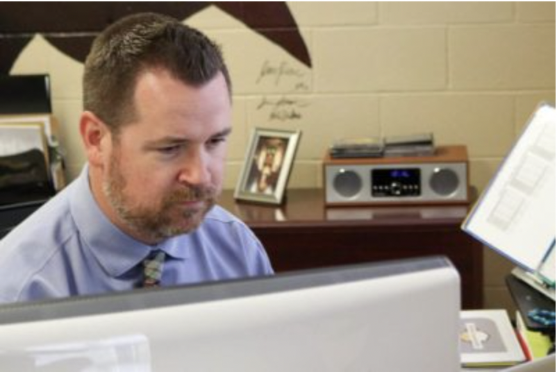 Dr. Lucas Lammer looks up a student in infinite campus in his office.