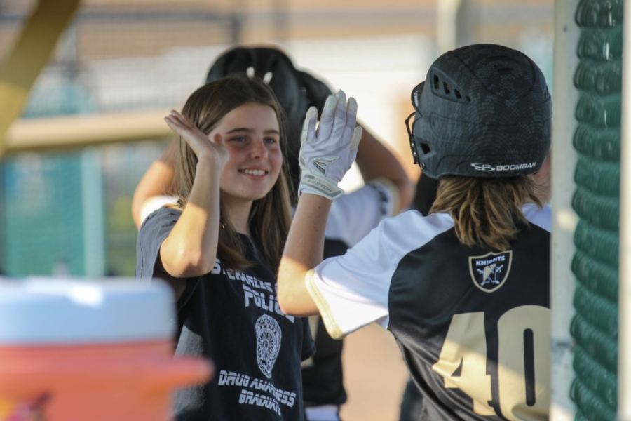 Two JV softball players high five during a game 