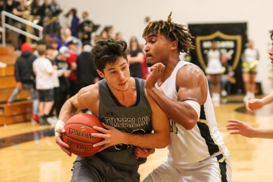 Senior Trenton Oglesby leans against a Timberland HS forward as he drives in towards the hoop.