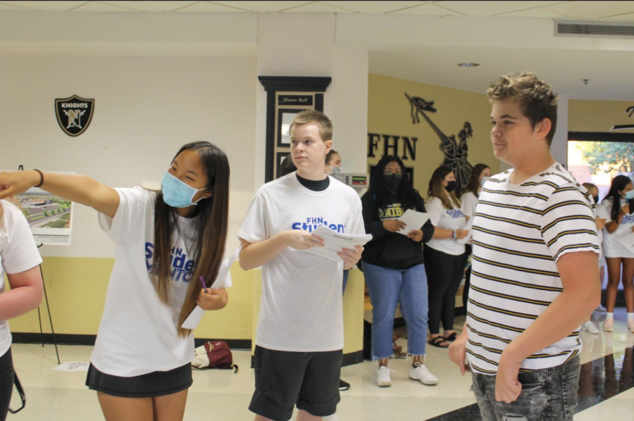 Junior Hailey Zhang and senior Ian Pierce direct a student in the lobby.