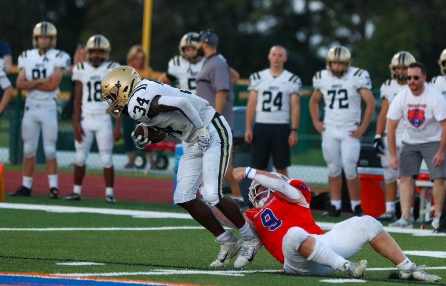 FHN's Varsity Player #34 carries the football and avoids a tackle from North Point's #9. 