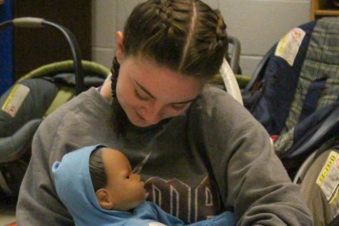 Sophomore Ellie Barnum cradles a baby in the nursery on Nov 17. She supports the head, while making sure it feels comfortable. Students who take the Child Development class are taught that when it comes to picking up babies it’s important to be careful, because of how delicate they are. “Having a basic foundation of what a healthy pregnancy looks like and how to have positive interactions with children is something that benefits every single person on this planet” Mrs.White said.