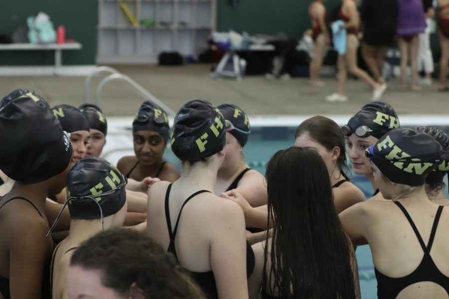 The girls swim team circles in a team huddle before their swim meet on Dec. 1st 