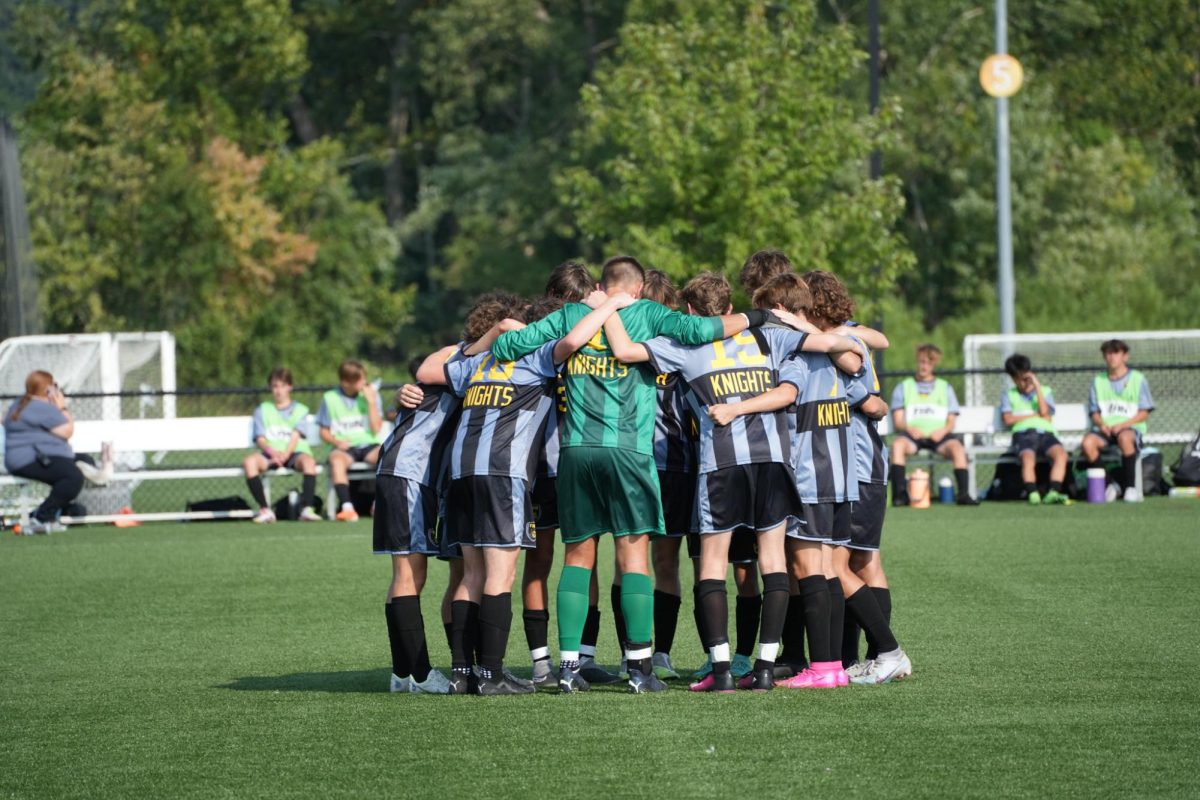 The boys soccer team meets on the field during a game. 