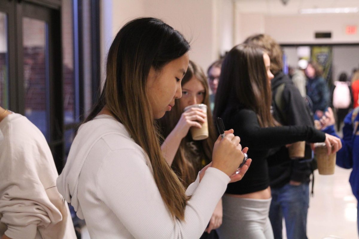 Senior Hailey Zhang sells coffee at Sun club coffee fundraiser.