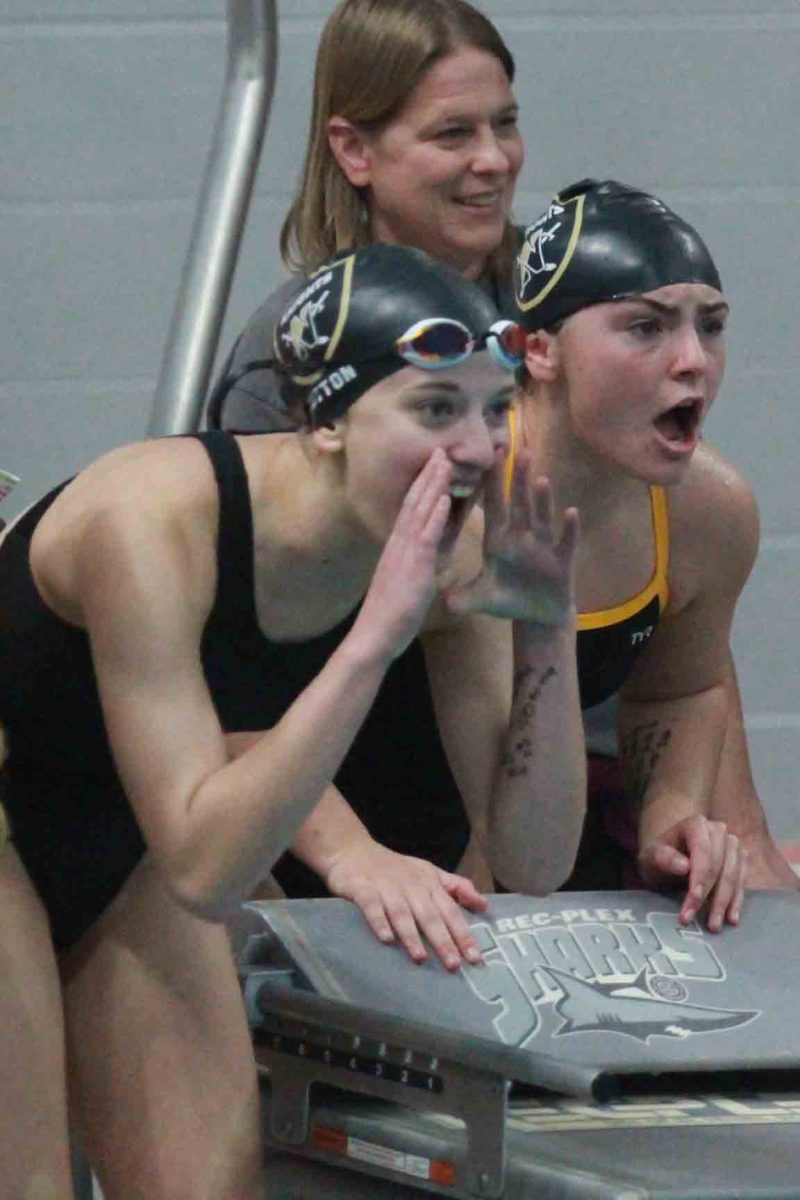 Seniors Hannah Button and Sailor Sulin cheer on their teammates during the Dec. 15 swim meet.