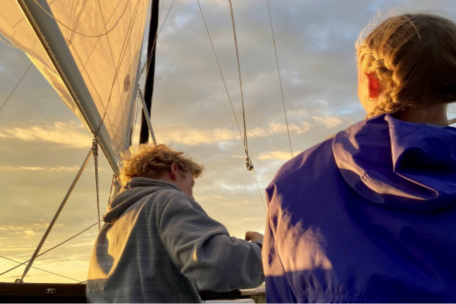 Siblings Carter and Macey Hood stand on a boat while sailing and admire the view.