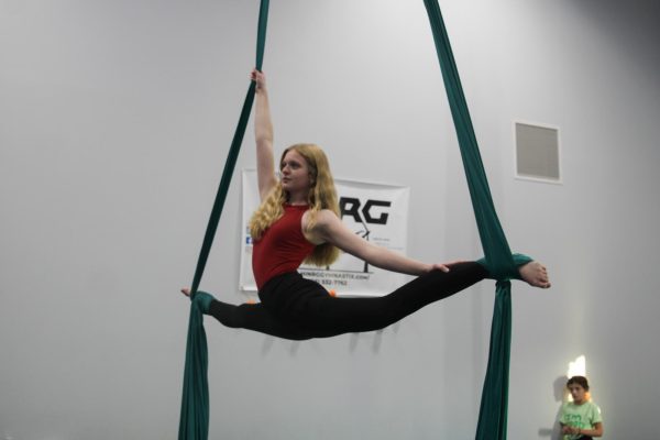 Sophomore Lucy Schmid performs her aerial silk routine at HI-NRG Gymnasium on Sept. 25 2024. Schmid has been performing aerial for the past 5 years after seeing older gymnasts perform while she was doing gymnastics while she was younger. “I would always watch the silks and just think about how cool it looked, so I tried it and have loved it ever since,” Schmid said.