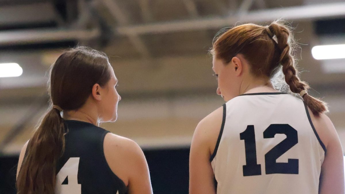 Seniors Camille Krekeler and Sophia Manzella exchange a moment on the side of the court in the girls basketball tryouts. 