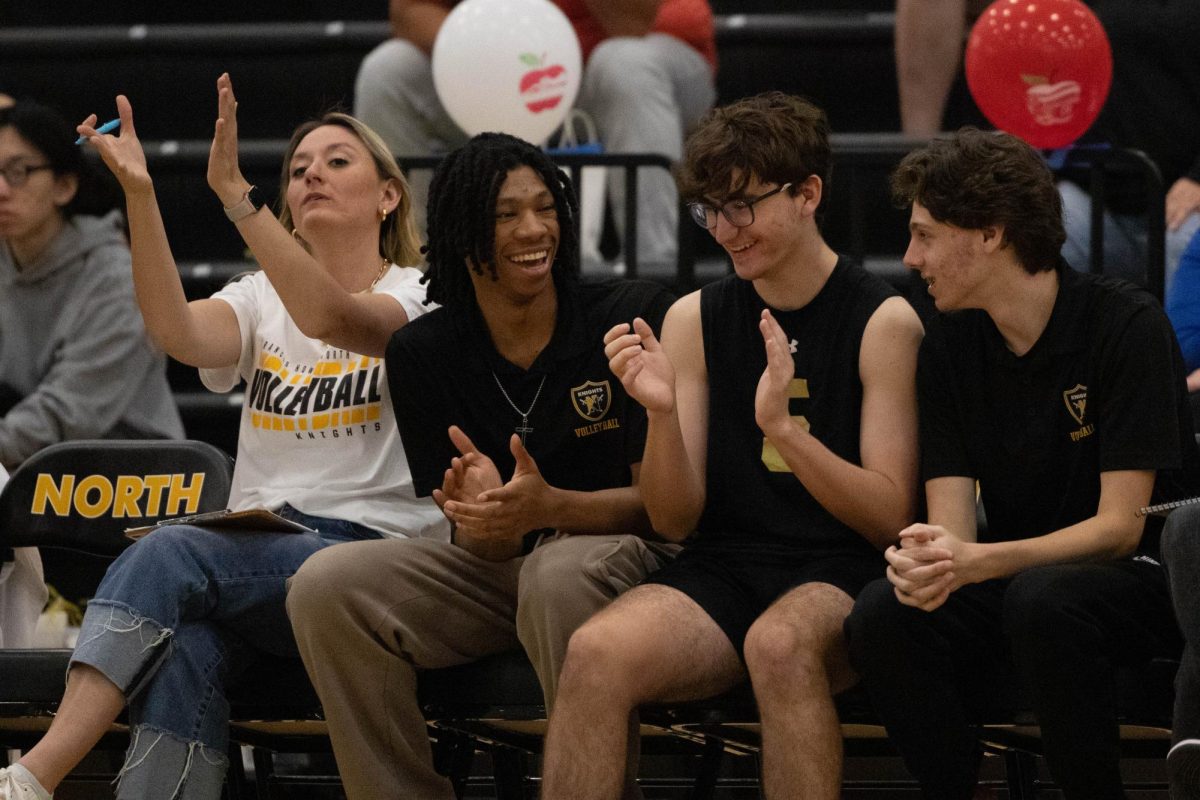 Coach Molly Wade, AJ Kincade, John Dittmar and Brandon Puzniak clapping for teammates at home game against LIberty on April 30.