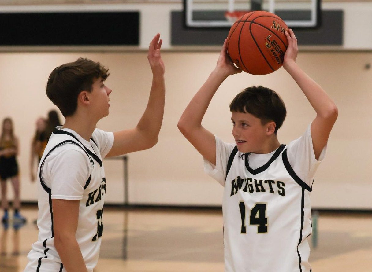 Cohen Oster instructs younger Brother Beckett Oster on shooting while playing  basketball. 